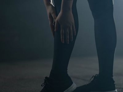 Athlete stretching leg muscles in a dark gym environment.